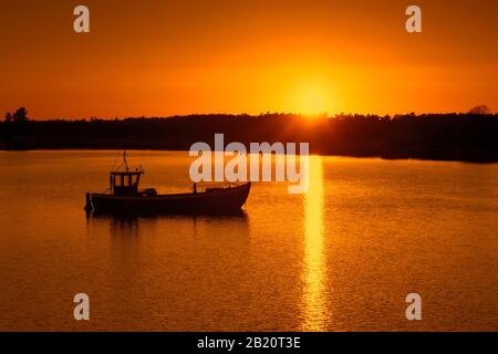 Imbarcazione da pesca silhouette contro il tramonto, isola di Ummanz, comune nel distretto di Vorpommern-Rügen nel Mecklenburg-Vorpommern, Germania Foto Stock