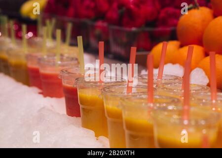 Foto di un gruppo di tazze di plastica con succhi di frutta freschi pronti per il consumo. Messa a fuoco selettiva Foto Stock