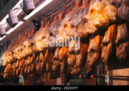 Foto di scorta di un mucchio di prosciutto iberico gambe appese a uno stallo del mercato Foto Stock