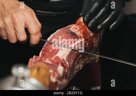 Foto di scorta di una mano di un maestro taglierino iberico. Sta tagliando il prosciutto iberico Foto Stock