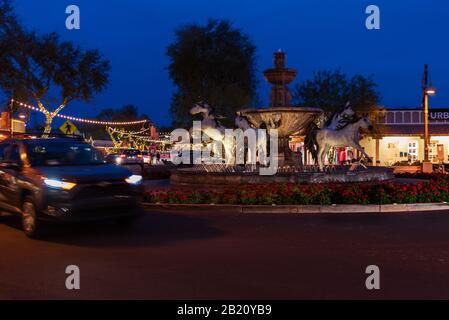 Automobili che guidano dalla fontana del cavallo di bronzo sulla 5th Avenue nella città vecchia Scottsdale, Arizona. Foto Stock
