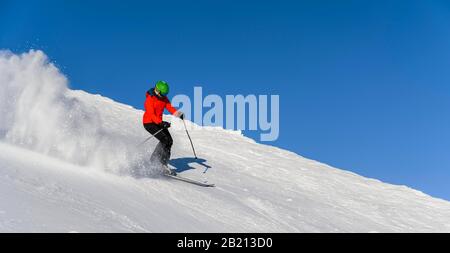 Sciatore discesa ripida pendenza, pista nera, cielo blu, SkiWelt Wilder Kaiser, Bressanone im Thale, Tirolo, Austria Foto Stock