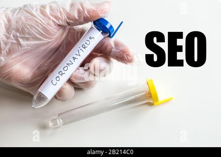 Flaconcino con coronavirus in mano e la parola "EO". Concetto di utilizzo del virus e paura di esso per scopi aziendali Foto Stock