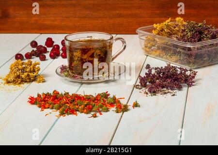 Tè appena estratto da erbe medicinali. Erbe medicinali essiccate per la salute. Lobaznik ordinario, origano, fiori marigold, rosato su un tavolo di legno. Ph Foto Stock