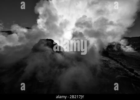 Un geyser ruba un masso all'alba mentre il sole filtra attraverso il vapore, El Tatio Geyser Field, Altiplano, Atacama Desert, Antofagasta Cile Foto Stock