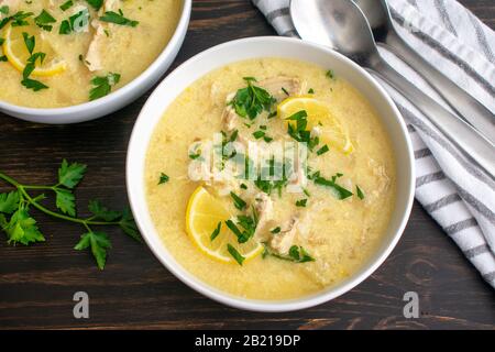 Zuppa Avgolemono (nota anche come zuppa greca di pollo al limone): Ciotole di zuppa greca tradizionale con pollo, riso e limoni Foto Stock