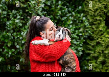 Giovane ragazza bianca caucasica con un piccolo carino Boxer Puppy fuori nel giardino. Preso A Vancouver, British Columbia, Canada. Foto Stock