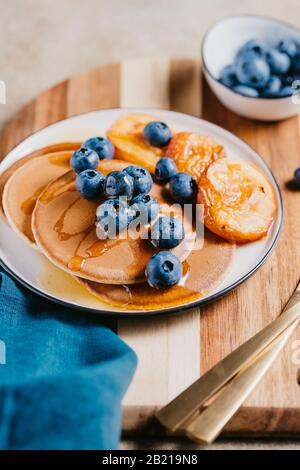 Primo piano di frittelle con pesche alla griglia, mirtillo fresco e miele. Foto Stock