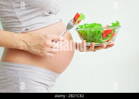 alimentazione sana e gravidanza. insalata di verdure e pancia della donna incinta. Gravidanza Nutrizione. Vegetarismo e gravidanza Foto Stock