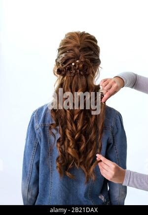 Capelli ricci ondulati. Parrucchiere che fa acconciatura per capelli rosso marrone donna con capelli lunghi utilizzando pettine su sfondo bianco. Parrucchiere professionale Foto Stock