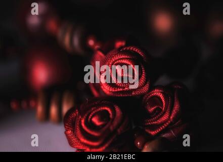 Primo piano di rose rosse fatte da nastri che fanno parte di una collana italiana, colore Foto Stock