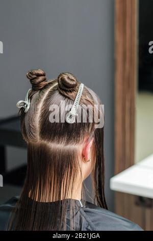 Dividere i capelli della donna in sezioni con le clip durante l'estensione dei capelli nel salone di bellezza. Foto Stock