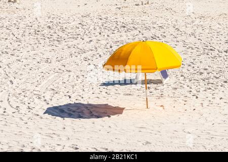 Mare, Florida spiaggia durante la giornata di sole in villaggio con vista ad alto angolo di ombrello giallo e ombra sulla sabbia Foto Stock