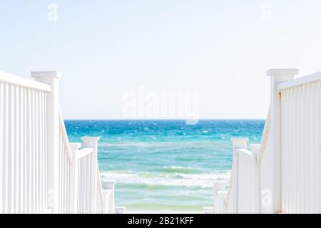 Lungomare, Florida bianca ringhiera scalinata in legno passerella giù vista dell'architettura sulla spiaggia oceano vista sfondo durante la giornata di sole e orizzonte Foto Stock