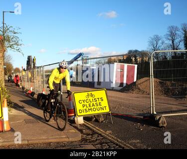 Febbraio 2020 - giro in bici attraverso un Ciclista smontare segno su Cumberland Road nel centro di Bristol, accanto ai lavori di riparazione tempesta Foto Stock