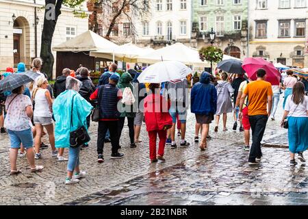 Lviv, Ucraina - 31 luglio 2018: Storica città Ucraina nel parco piazza del mercato della città vecchia con persone che camminano su strada acciottolata su ombrelloni piovosi Foto Stock