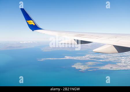 Keflavik, Islanda - 20 giugno 2018: Icelandair aereo in cielo blu con vista dalla finestra vista ad angolo alto sull'oceano Atlantico artico e la città, montagne i Foto Stock