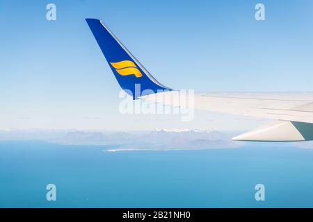 Keflavik, Islanda - 20 giugno 2018: Aereo Icelandair in cielo blu con vista dalla finestra vista ad angolo alto sull'oceano Atlantico artico e le montagne in h. Foto Stock