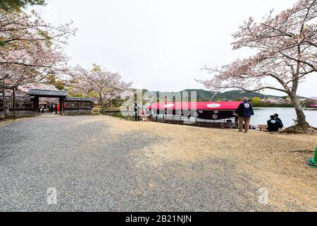 Kyoto, Giappone - 12 aprile 2019: Alberi di fiori di ciliegio del lago Osawa-no-Ike in primavera nella zona di Arashiyama dal Tempio Daikakuji con barca a drago rossa Foto Stock