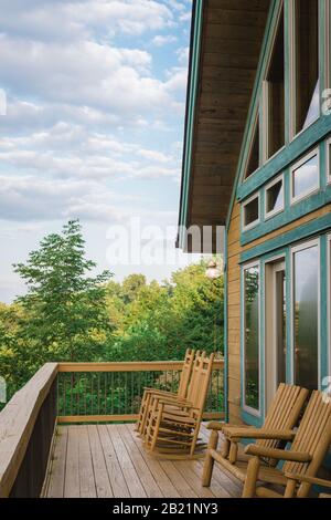 Sedie a dondolo attendono gli ospiti su questo portico della cabina di montagna vicino alle Smoky Mountains della Carolina del Nord. Foto Stock