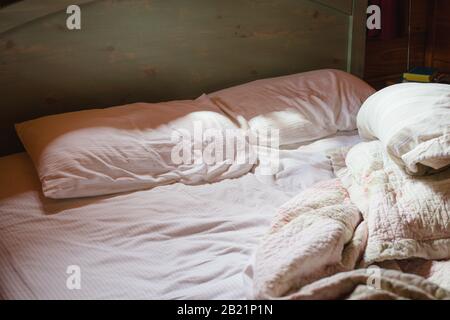 Un letto non fatto sembra caldo e accogliente in questo pigro giorno Domenica a sud. Foto Stock