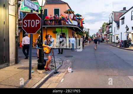 New Orleans, Stati Uniti - 22 aprile 2018: Louisiana famosa città città strada in serata con giovane ragazza che suona la chitarra di notte e la gente a piedi Foto Stock