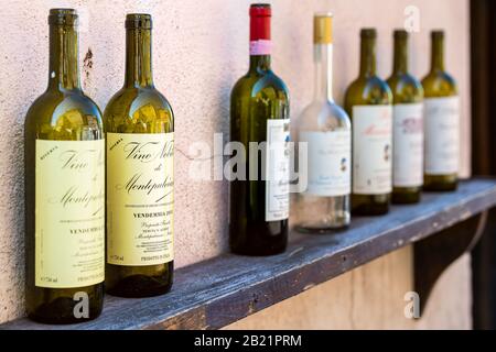 Montepulciano, Italia - 28 agosto 2018: Bottiglia vuota di Sangiovese rosso Riserva vino su ripiano in legno all'aperto sulla strada in bar o negozio locale ma Foto Stock