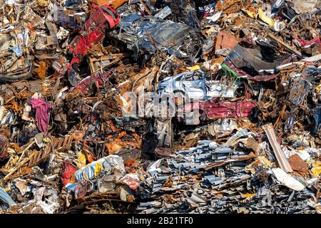 Un mucchio grande di metallo di scarto ad un deposito di riciclaggio. Auto non identificabili, coperture metalliche, e altri metalli assortiti tutti visibili. Foto Stock