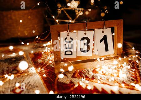 Calendario a foglia libera con la data del 31 dicembre in una garland e bokeh giallo primo piano, l'ultimo giorno dell'anno Foto Stock