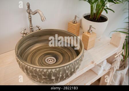 tondo scuro insolito slavello di pietra su un controsoffitto di legno e accessori da bagno organici riutilizzabili Foto Stock