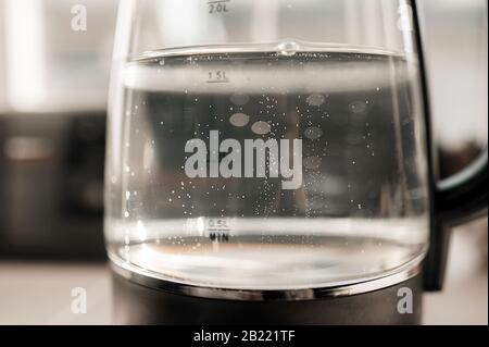 acqua bollente con bolle in una teiera trasparente con indicatori di livello Foto Stock