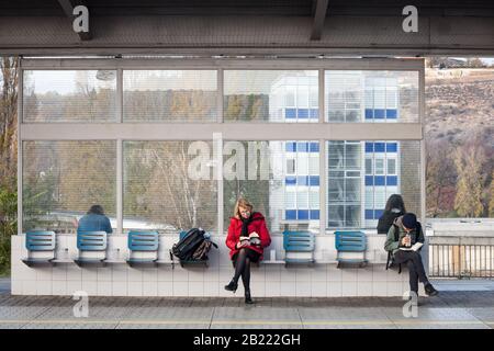 Praga, CECHIA - 3 NOVEMBRE 2019: Persone, donna anziana e un giovane, e pendolari, seduti in attesa di un treno a Holesovice stazione e lettura Foto Stock