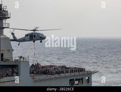 200226-N-KC192-1145 GOLFO ARABO (FEB 26, 2020) - Un MH-60S Sea Hawk, attaccato al Dragon Whales di Helicopter Sea Combat Squadron (HSC) 28, trasporta le forniture alla nave d'assalto anfibio USS Bataan (LHD 5) durante un rifornimento in mare, 26 febbraio 2020. Bataan è il fiore all'occhiello del Gruppo Bataan Amphibious Ready e, con l'unità di spedizione navale 26th imbarcata, è schierata nell'area di operazioni della flotta 5th degli Stati Uniti a sostegno di operazioni navali per garantire la stabilità e la sicurezza marittima nella regione centrale, Collegando il Mediterraneo e il Pacifico attraverso l'o dell'India occidentale Foto Stock