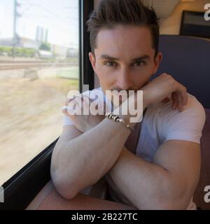 Giovane positivo bel uomo cavalcare un treno. Foto Stock