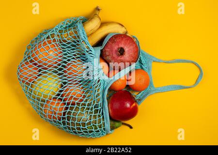 Concetto di assenza di rifiuti in plastica. Frutta fresca in un sacchetto di rete di maglia, vista dall'alto con copyspace. Borsa da shopping in mesh con frutta. Stile di vita sostenibile Foto Stock