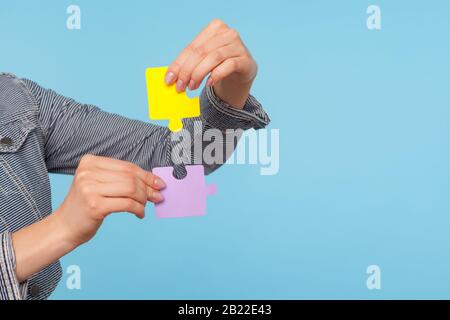 Closeup di mani femminili che tengono pezzi colorati di puzzle, due parti del puzzle di uno, simbolo di collegamento e Unione, soluzione di affari, associazione. In Foto Stock