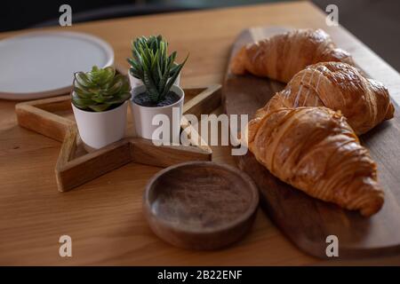 Succulenti, croissant, mela rossa su un tavolo di legno. Colazione gustosa e sana. Pasticceria francese. Foto Stock