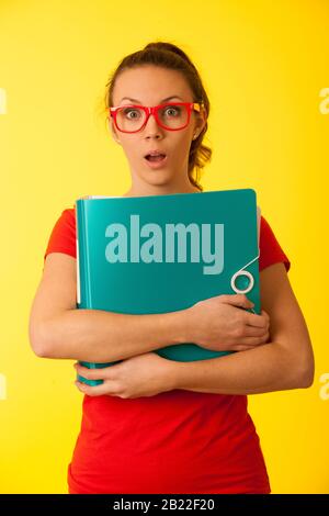 Giovane donna geek in t shirt rossa su sfondo giallo vibrante sotto stress Foto Stock