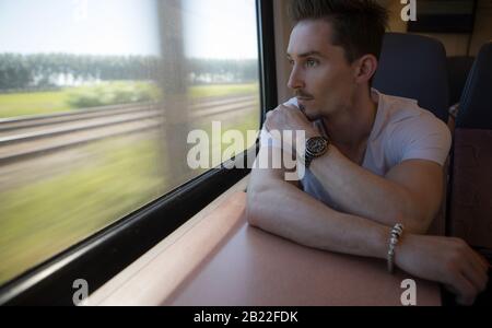Giovane positivo bel uomo cavalcare un treno. Foto Stock