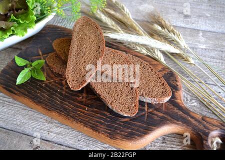 Fette di pane biologico raffinato decorate con cereali naturali su tavola rustica Foto Stock