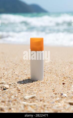 Bottiglia di crema solare sulla spiaggia di sabbia sul mare. Salute della pelle protezione solare concetto. Cosmetici con ingredienti naturali. Foto Stock