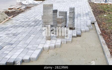 Blocchi di calcestruzzo e un cordolo sono installati professionalmente sulla base di fondazione di sabbia livellata. Pila di blocchi di calcestruzzo pronti per la posa Foto Stock