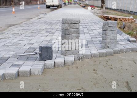 Blocchi di calcestruzzo e un cordolo sono installati professionalmente sulla base di fondazione di sabbia livellata. Pila di blocchi di calcestruzzo pronti per la posa Foto Stock