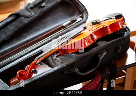 Violino con fiocco che si stende in una foddle aperta nera sul tavolo. Concetto di gruppo di strumenti musicali classici, nessuno. Strumento sicuro Foto Stock