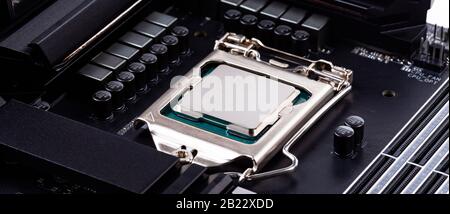 Semplice CPU high end senza marchio in argento in socket, closeup di superficie, scheda madre moderna grandangolare prodotto shot. Installazione di un nuovo processore, hardware Foto Stock