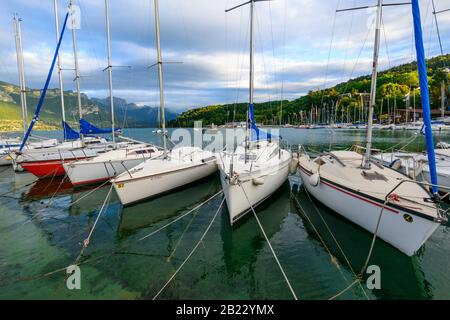 Barche a vela ormeggiate sul lago di Annecy, uno dei laghi più grandi in Francia, conosciuto come il lago più pulito d'Europa, al tramonto. Foto Stock