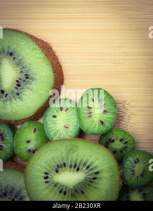 Frutta kiwi a fette e bacche kiwi disposti su un tagliere di legno. Foto Stock