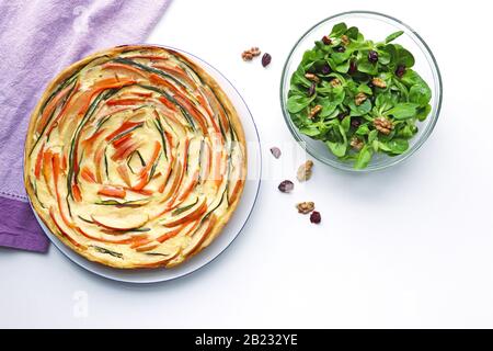 vista dall'alto di una torta di verdure intera e di una ciotola con lattuga agnelli su una tavola bianca Foto Stock