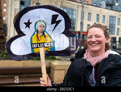 Sorridente protestante che tiene in su una bandiera dell'Influencer Greta Thunberg dopo la marcia per il clima e lo sciopero della scuola a Bristol Regno Unito in febbraio 2020 Foto Stock