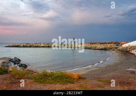 Baia con spiaggia con lettini e ombrelloni a Platamonas in Grecia Foto Stock